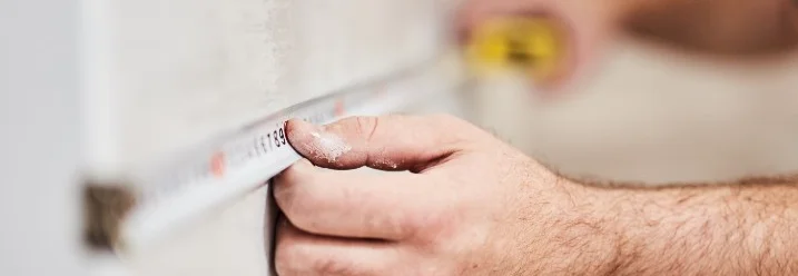 Person misst Wand mit Zollstock aus